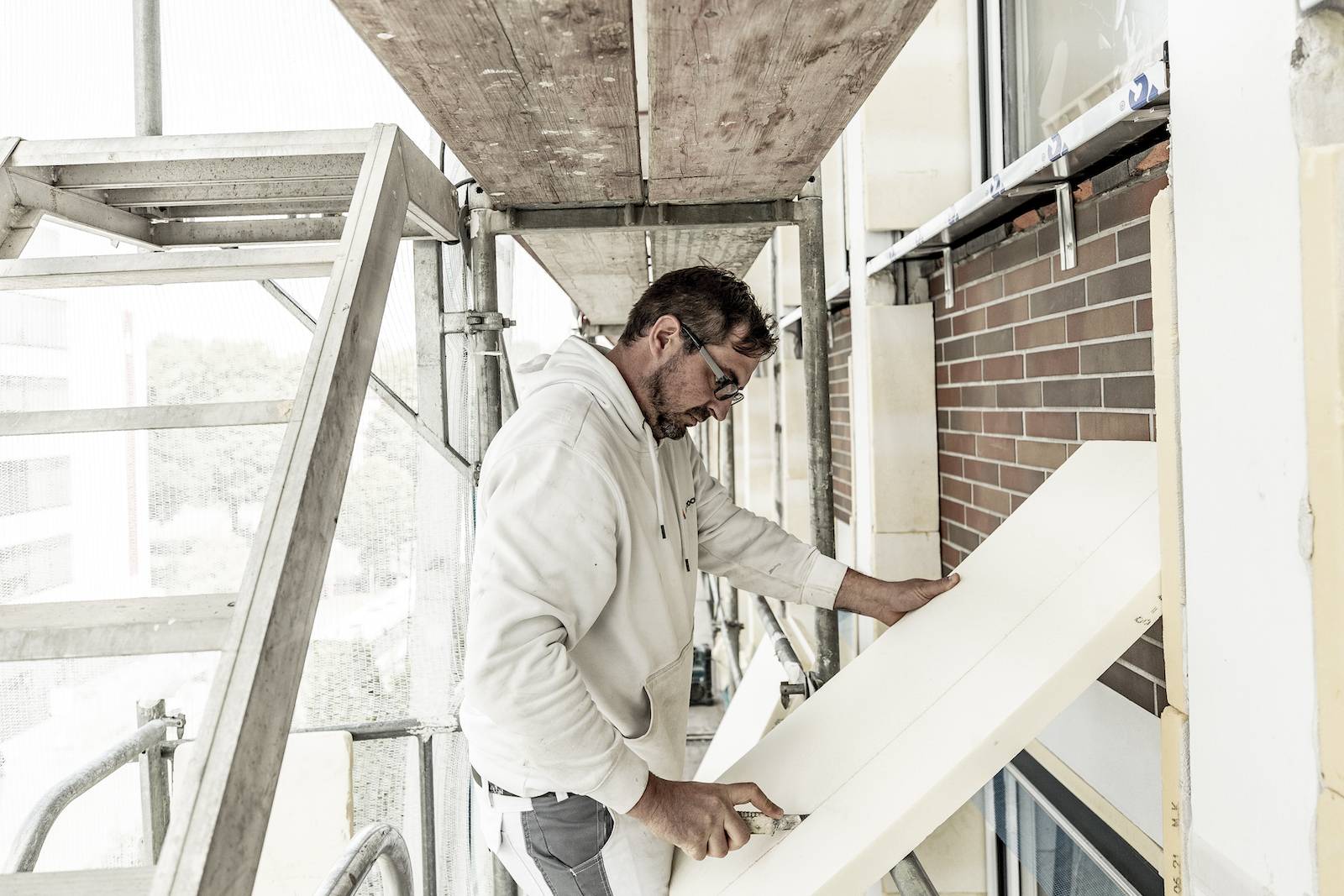 Arbeiter montiert Dämmung an einer Fassade.