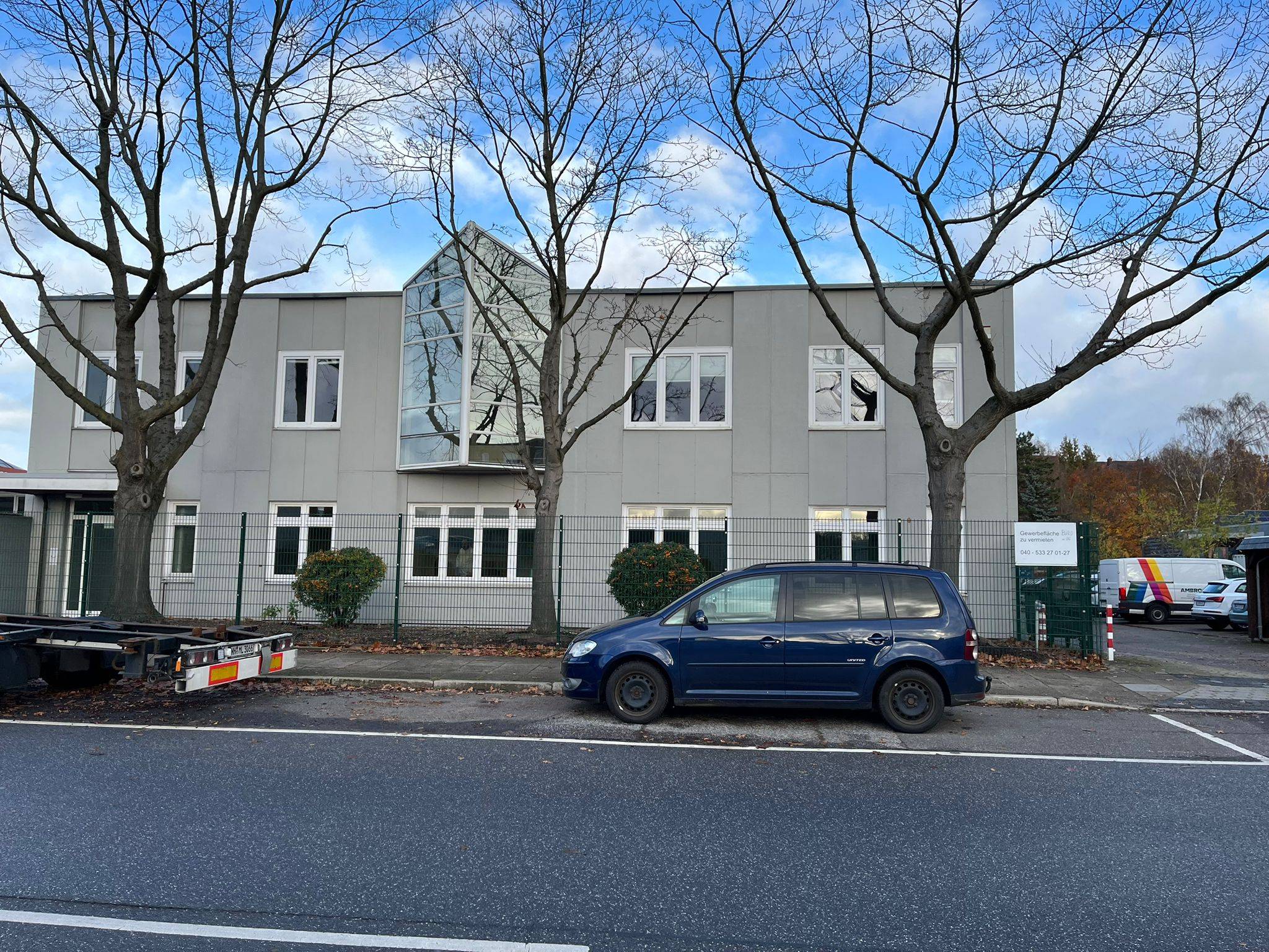 Modernes Gebäude mit Bäumen und Fahrzeugen davor