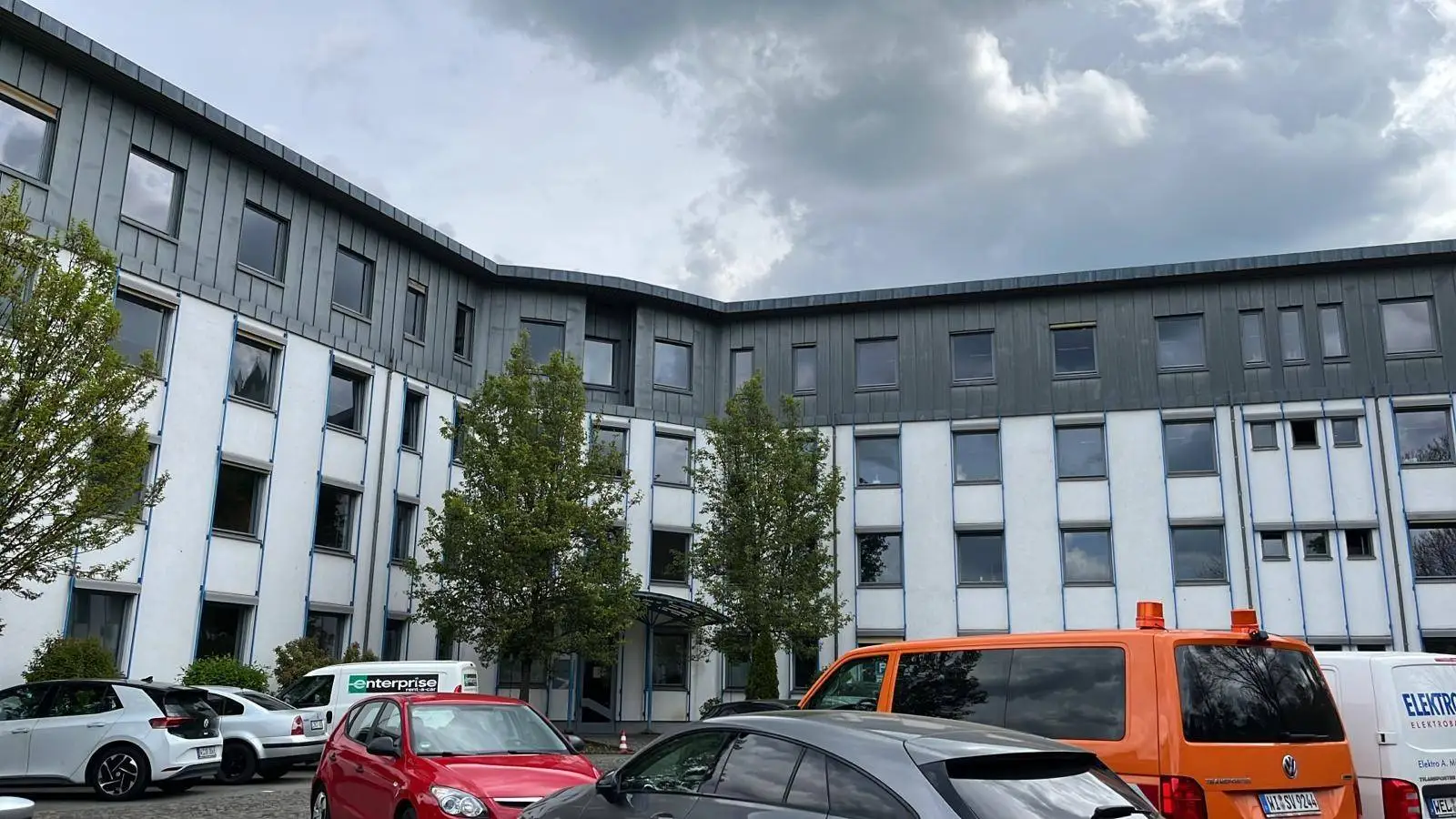 Modernes Bürogebäude mit Parkplatz und Autos