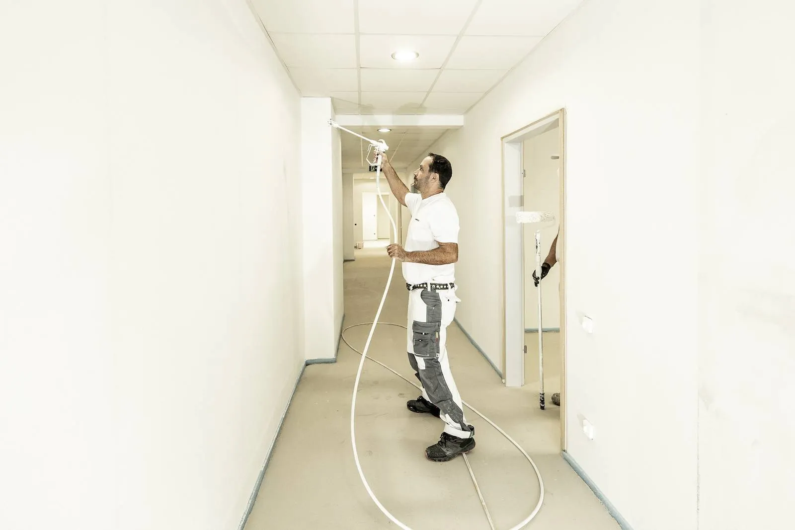 Maler sprüht Decke in hellem Flur